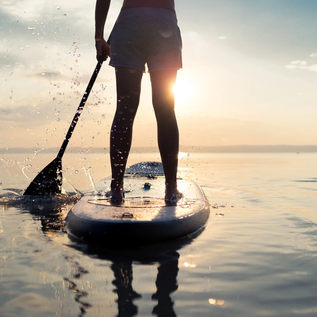 ragazzo di spalle che rema su una tavola di SUP a mare